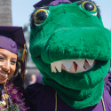 Graduate poses with the gator mascot at commencement