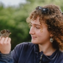 woman holding and looking at bird in nature