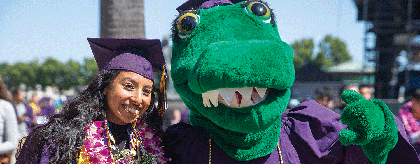 Graduate poses with the gator mascot at commencement