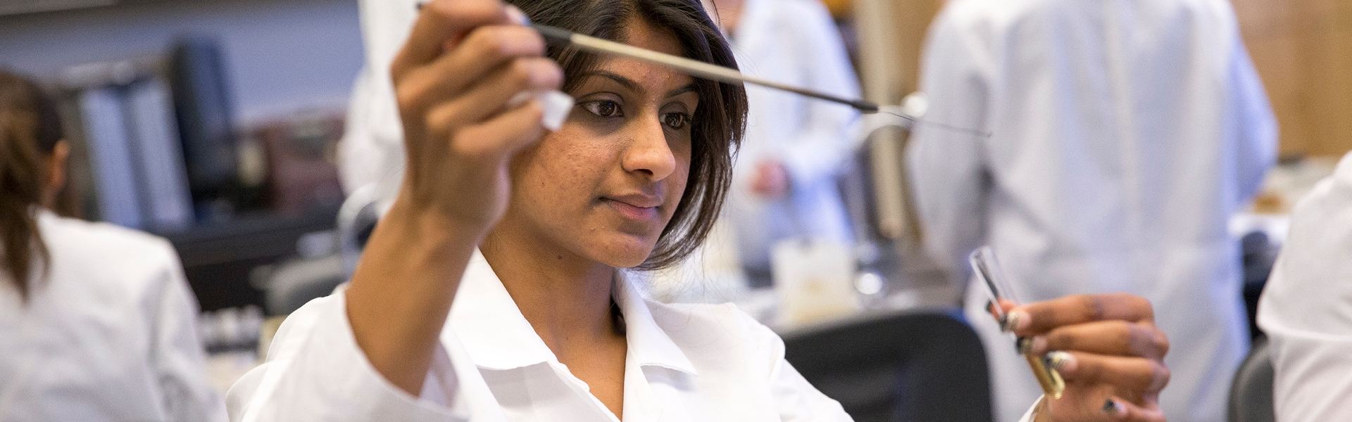 SF State student looking at a petri dish in a science lab.