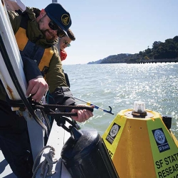 Two persons tying a buoy to a boat. 