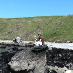 person sitting on a rock in the middle of the ocean marina